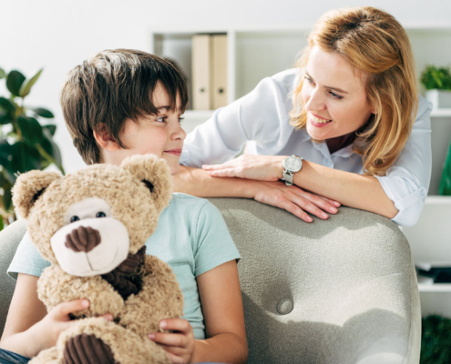 Front view of woman looking at a child holding a teddy bear